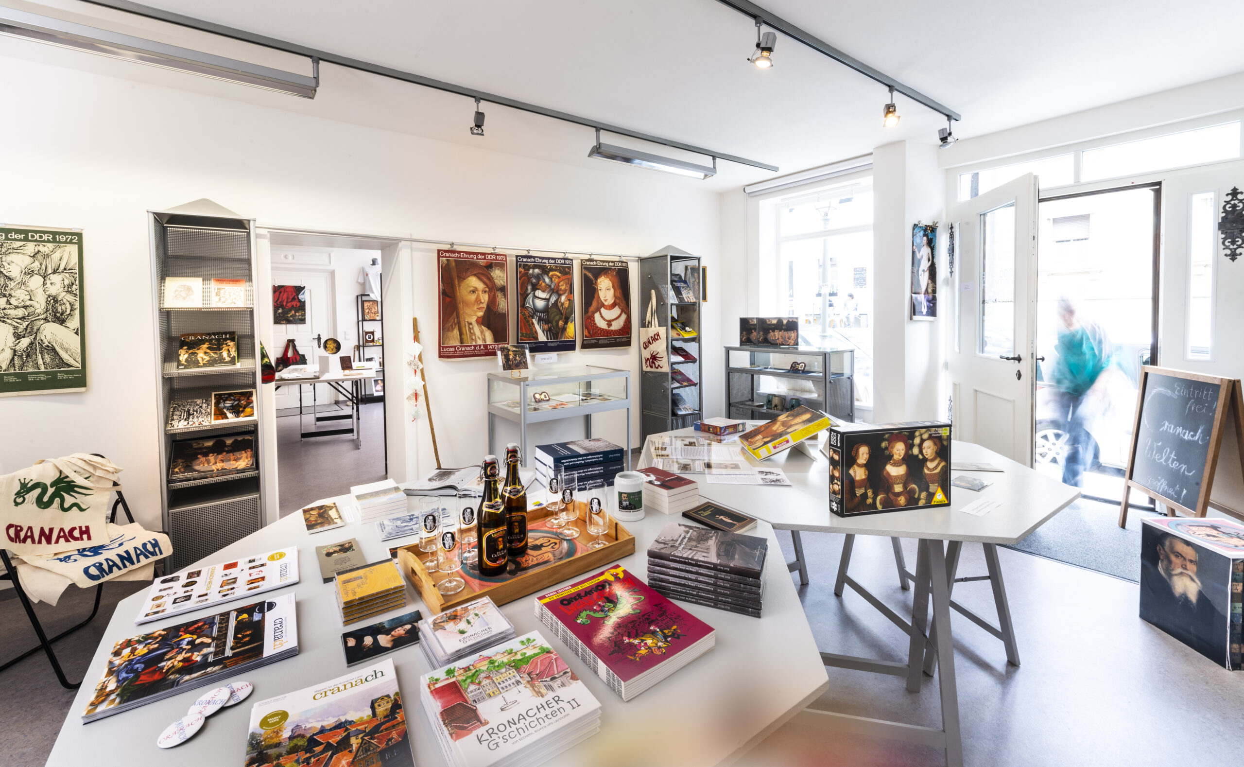 Ausstellungsraum der CRANACH-WELTEN mit Tischen voller Cranach-Bücher, -Objekte und -Souvenirs