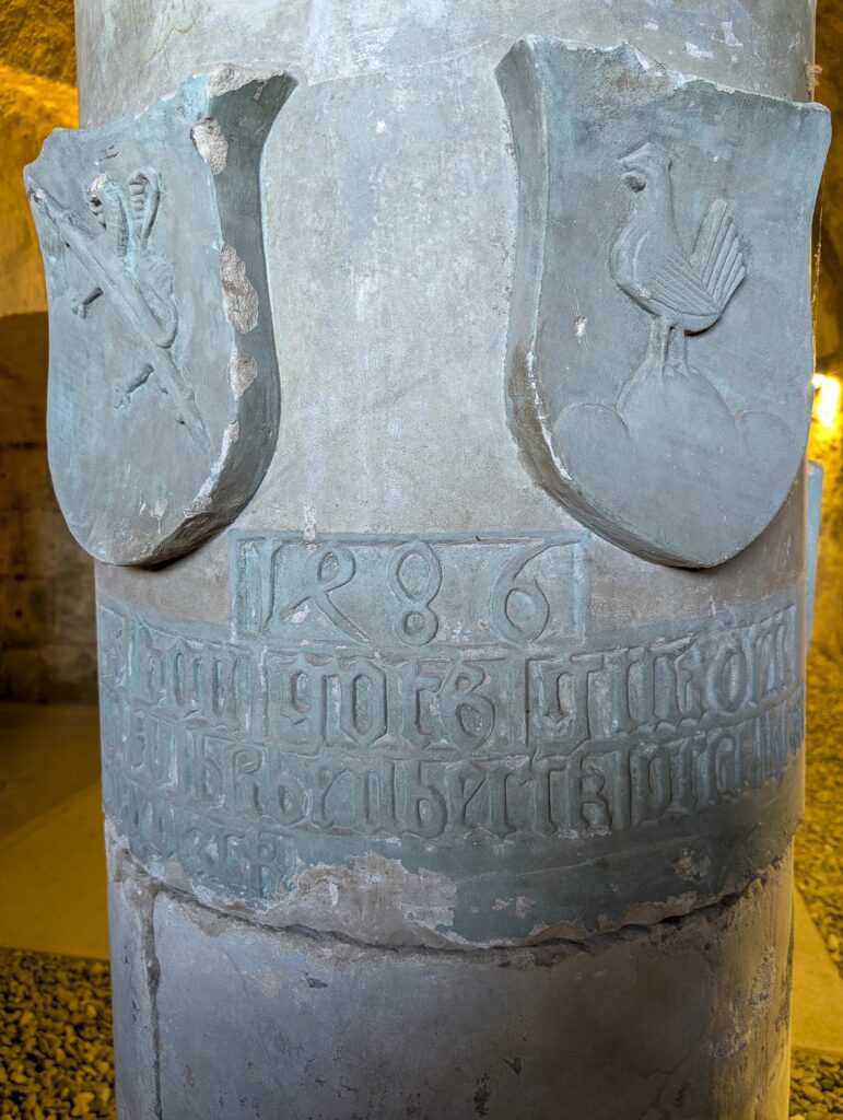 Rückseite der Säule mit zwei Wappenschilden, der Jahreszahl 1486 und einer beschädigten Inschrift