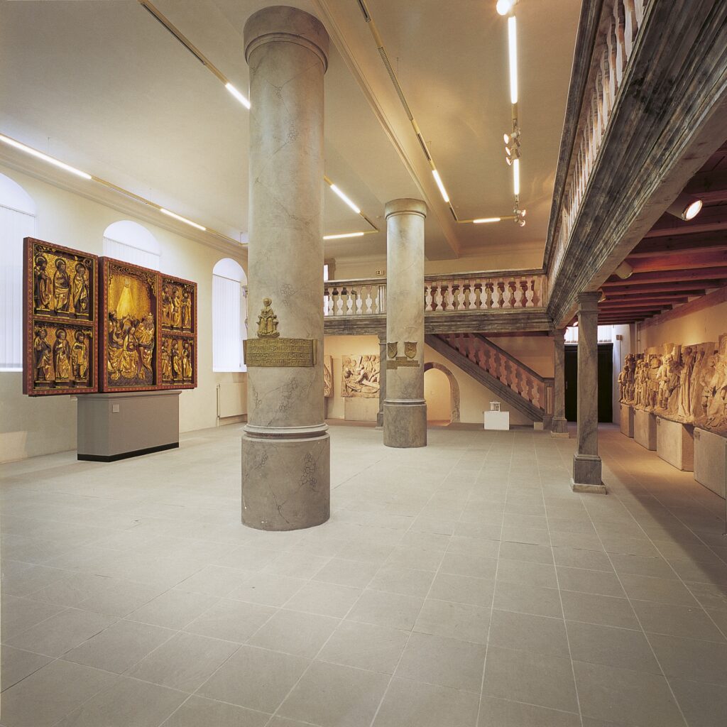 Heller Ausstellungsraum mit zwei Säulen, an denen Gipsabgüsse der Reliefs eingelassen sind